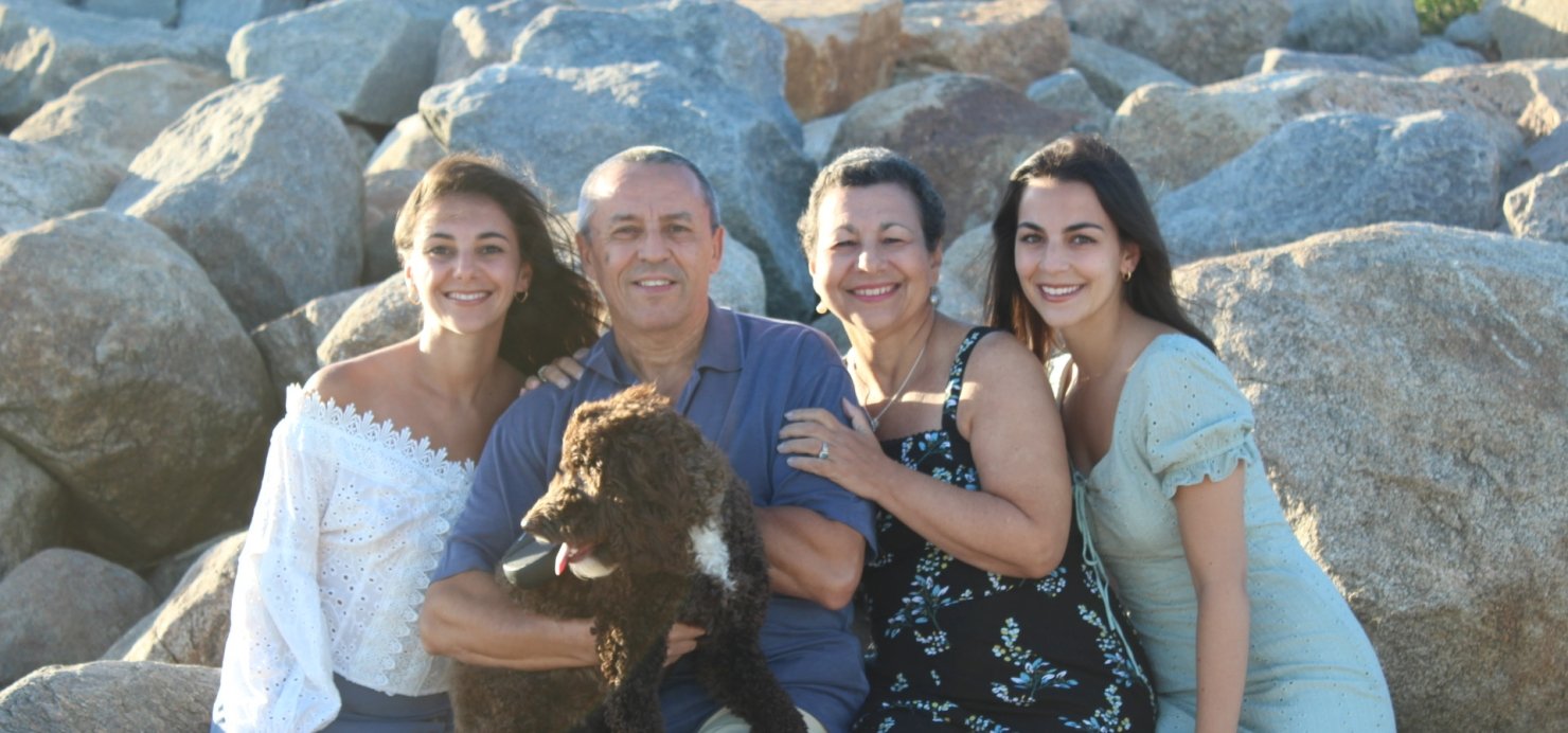 Family of four sit on rocks together, holding a dog