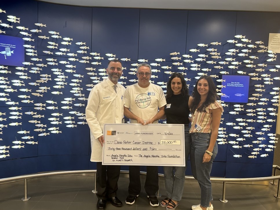 Family and doctor stand with a large check in front of the Zebrafish display