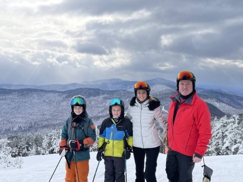 Julie stands with family on a snow-filled mountain wearing skis
