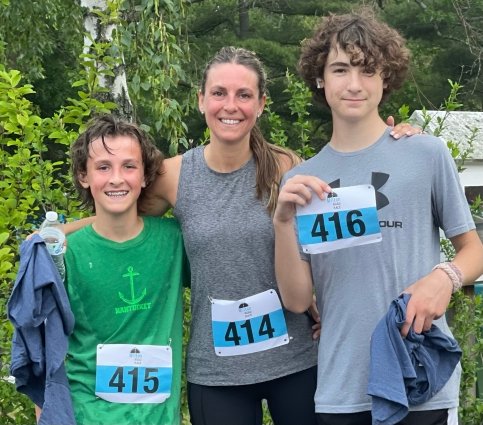 Julie and two teenagers wear running clothes and race bibs