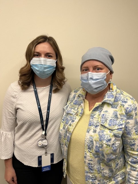 Aileen stands next to patient, both wearing masks
