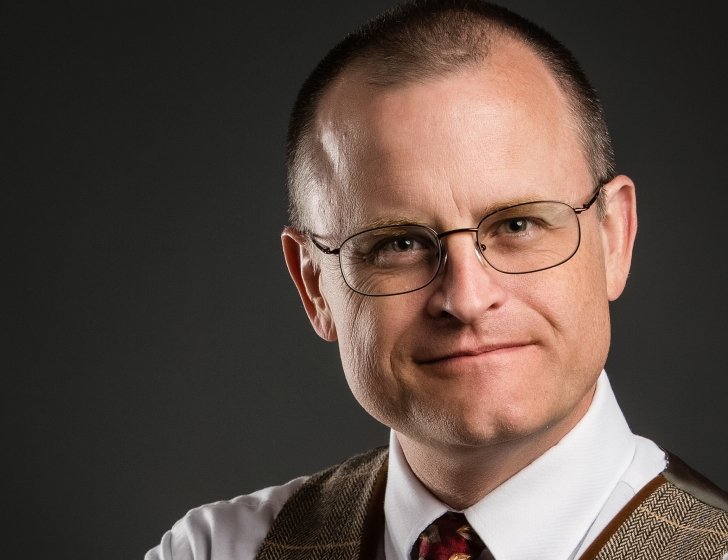 Russell wearing plaid vest and tie