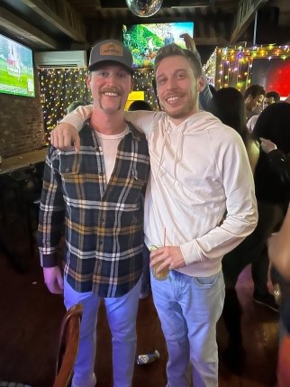 Sam with his arm around a friend at a bar