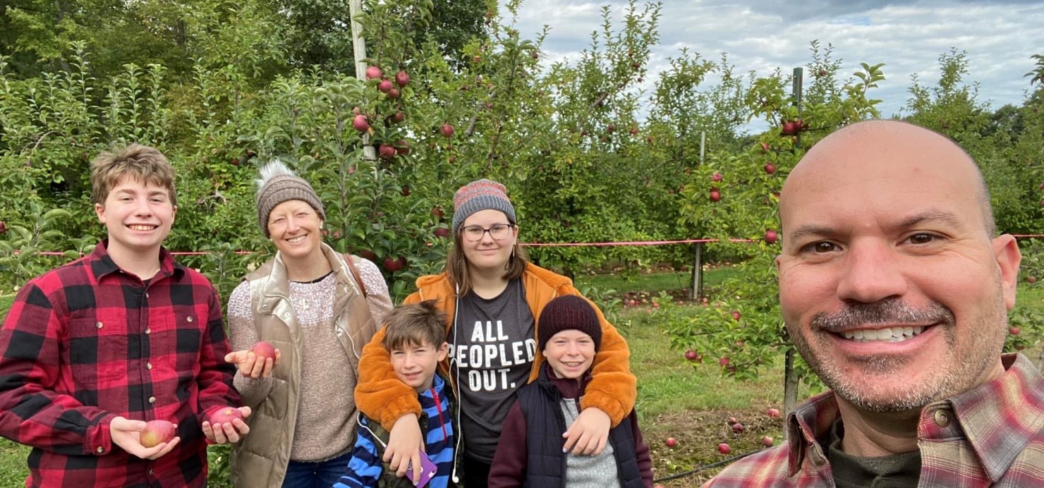 Family together stands in apple orchard