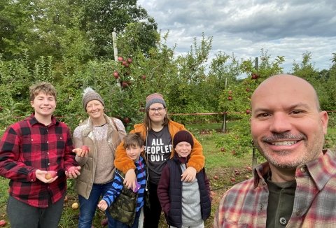 Family together stands in apple orchard