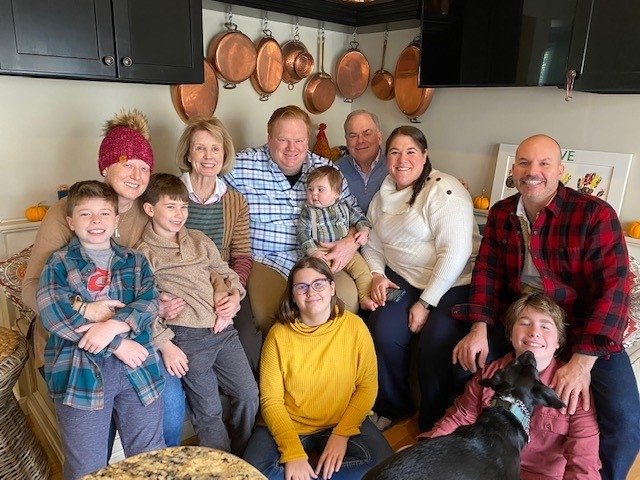 Hugues family sits together in kitchen posing for camera