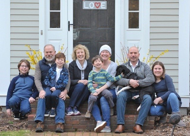 Family sits on front steps holding dog