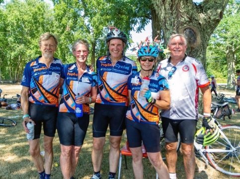 Five bikers stand together in front of a tree wearing 'PopSci Cycles' jerseys