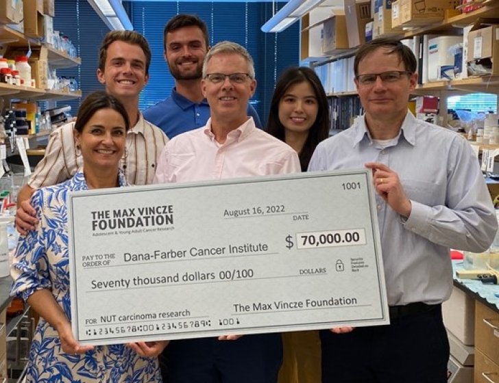 Vincze Family stands in lab holding large check