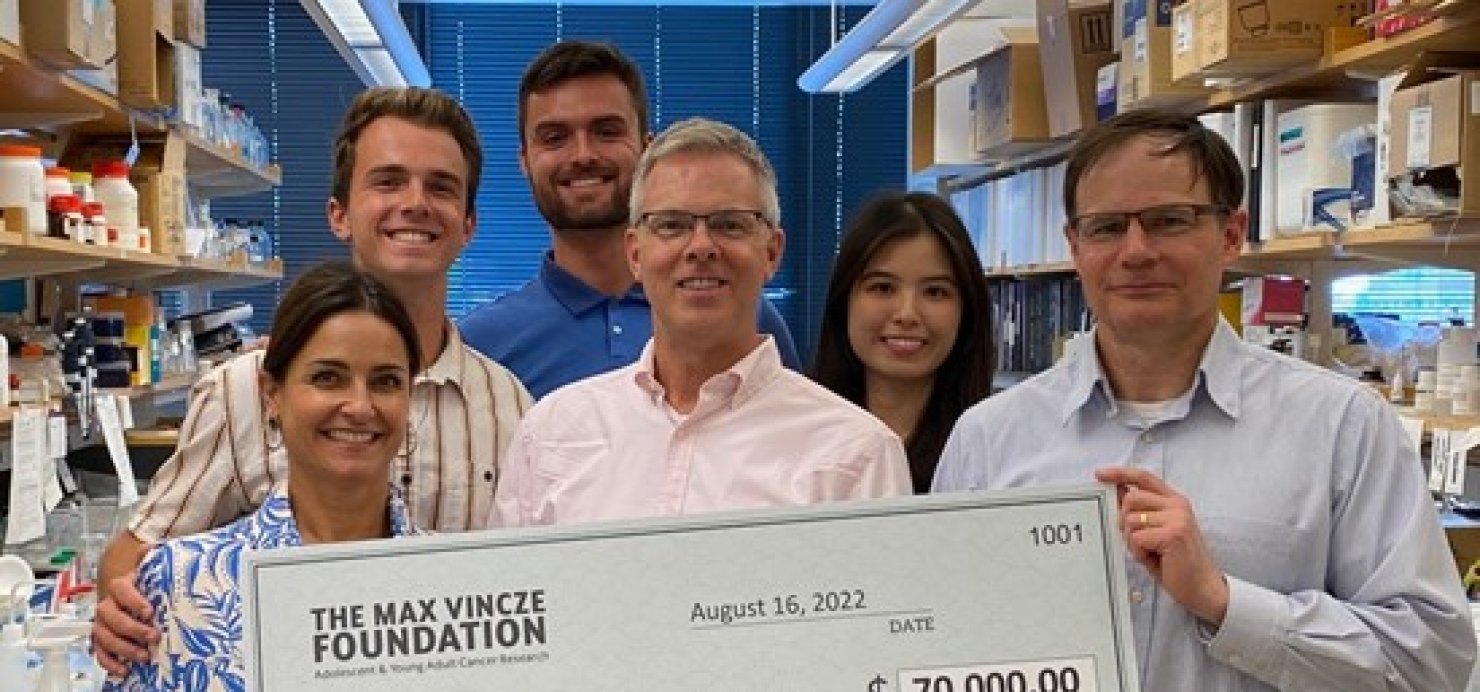 Vincze Family stands in lab holding large check