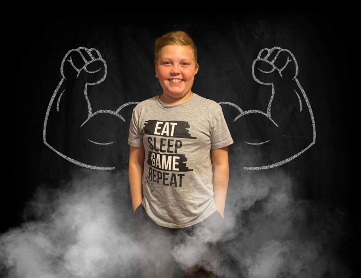 Evan stands in front of cartoon drawing of muscle arms