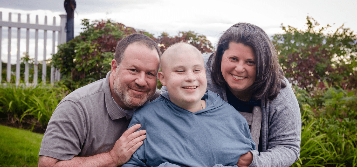 Zach stands with parents in front of a garden