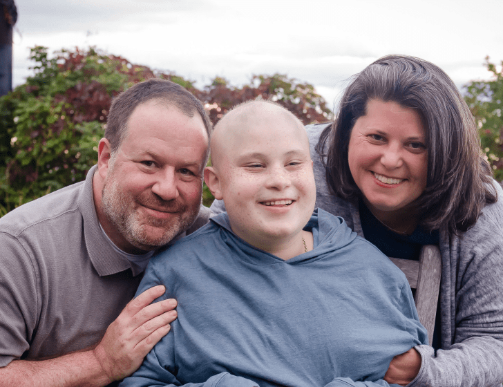 Zach stands with parents in front of a garden