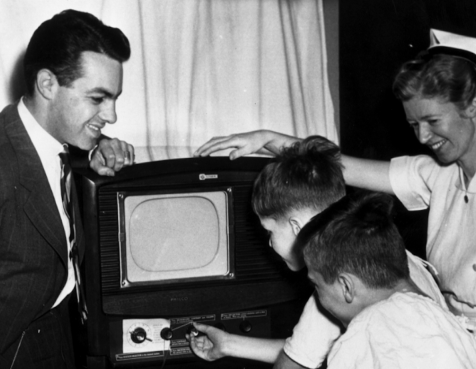Black and white photo of adults and children watching TV in the 1950s